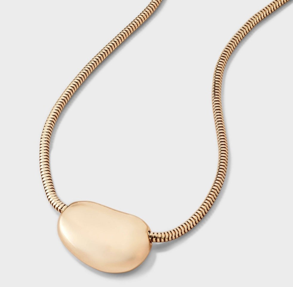 Gold-tone pendant necklace featuring a sleek snake chain and an oval-shaped charm