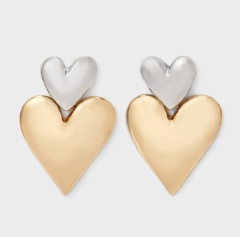 Two-toned heart stud earrings featuring a shiny silver-toned smaller heart on top of a larger gold-toned heart