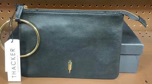 Thacker New York black leather clutch bag with a gold wrist ring.