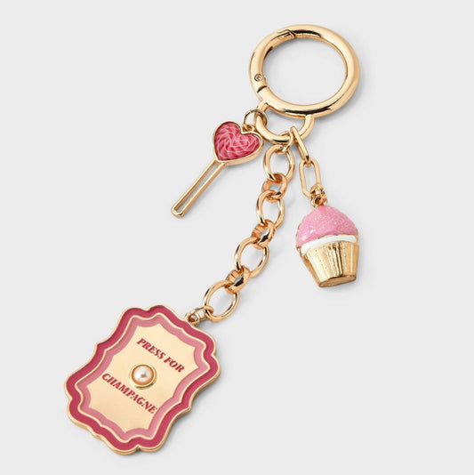 Gold-toned bag charm featuring a pink cupcake and a pink lollipop