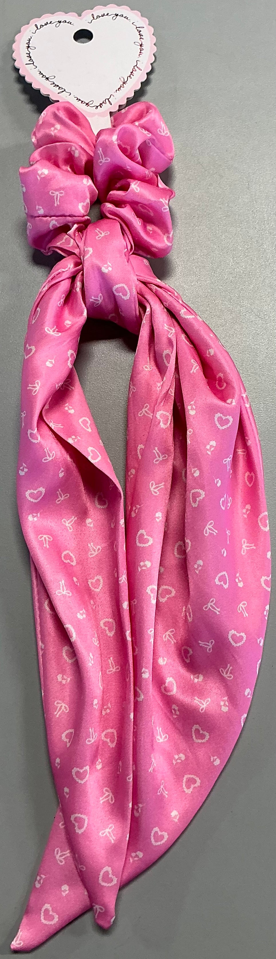 Pink satin hair twister featuring a white heart and bow print with long tails