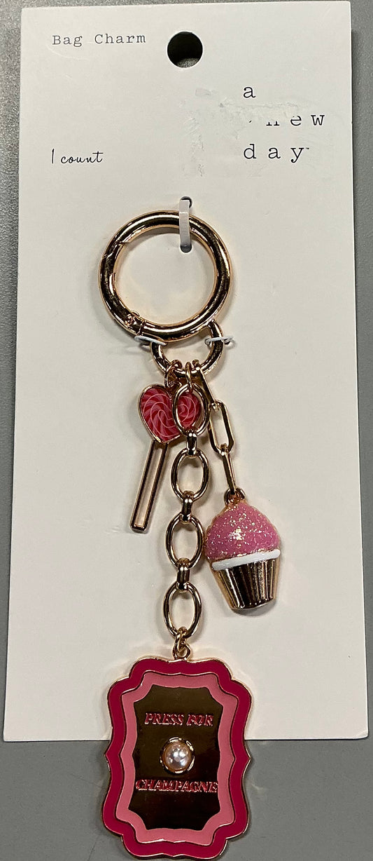 Gold-toned bag charm featuring a pink cupcake and a pink lollipop