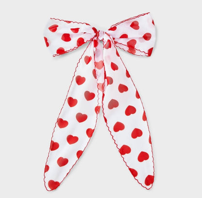 Hair bow featuring a red heart print and red stitching along the edges