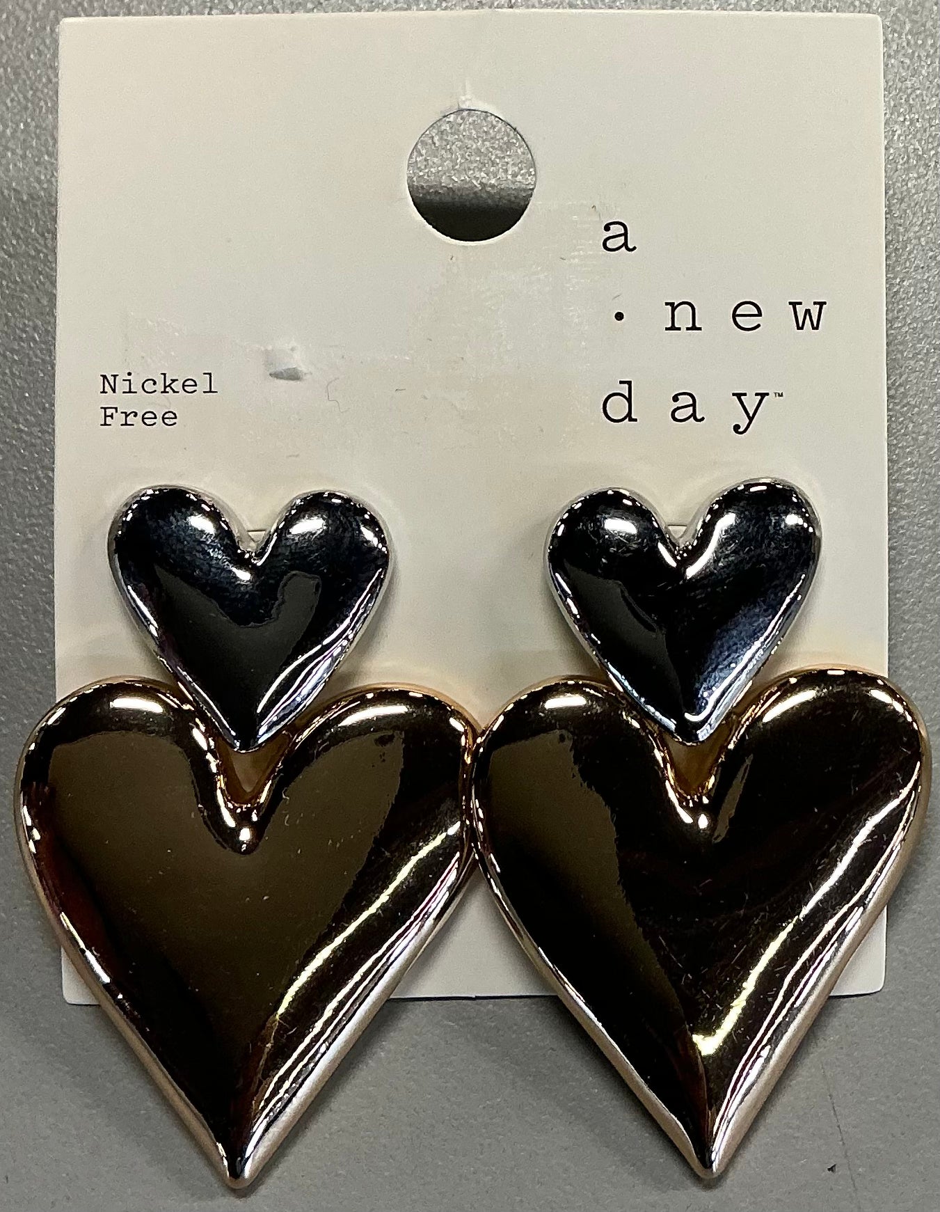 Two-toned heart stud earrings featuring a shiny silver-toned smaller heart on top of a larger gold-toned heart