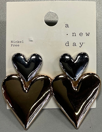 Two-toned heart stud earrings featuring a shiny silver-toned smaller heart on top of a larger gold-toned heart