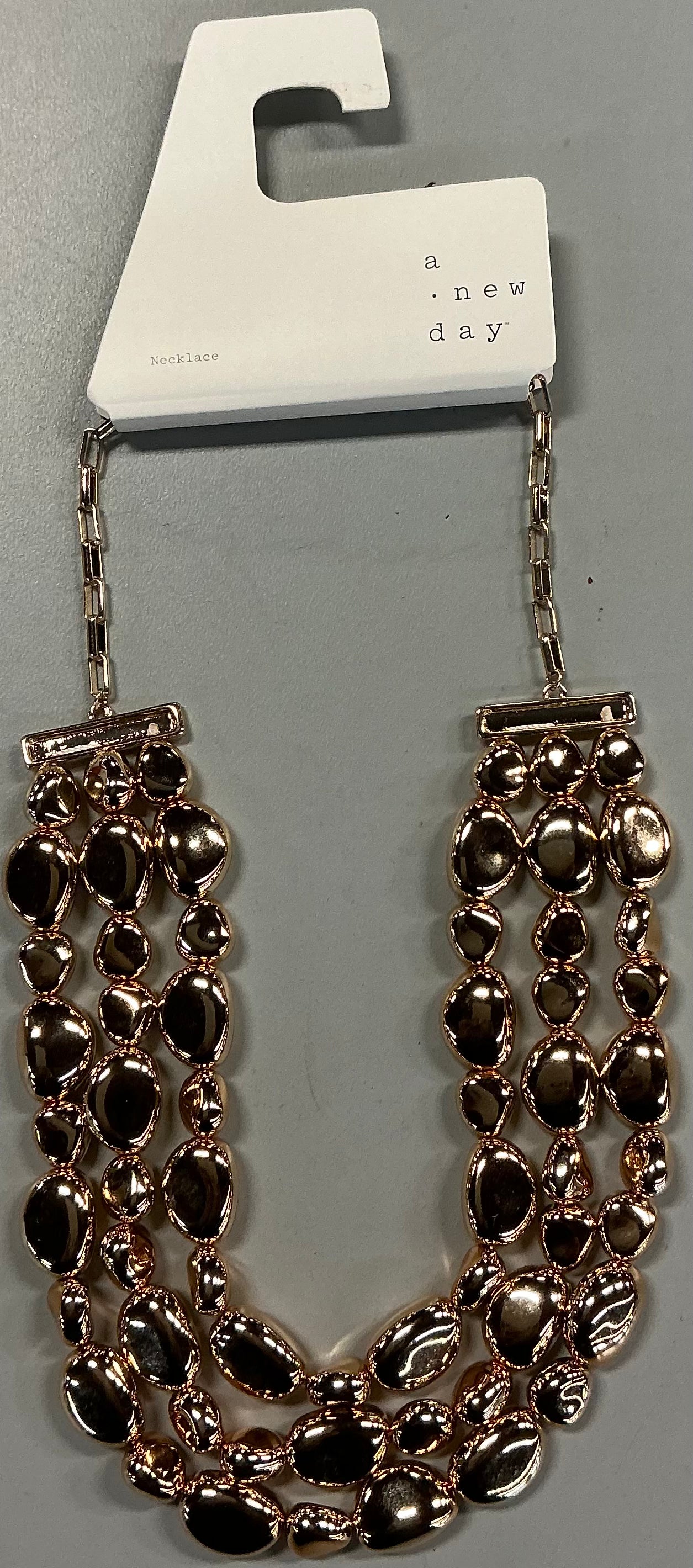 Gold-toned beaded drop necklace featuring three cascading strands of irregular pebble-like beads