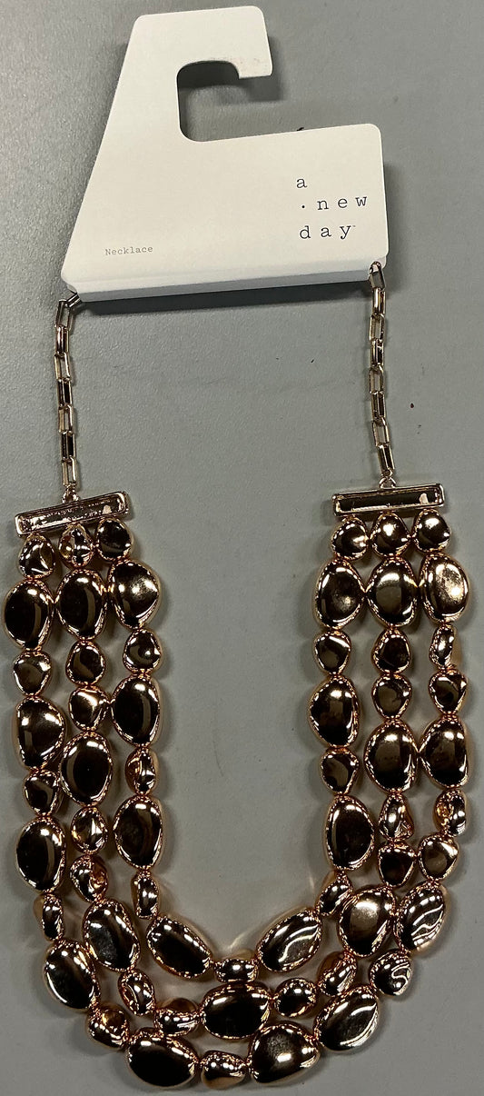 Gold-toned beaded drop necklace featuring three cascading strands of irregular pebble-like beads