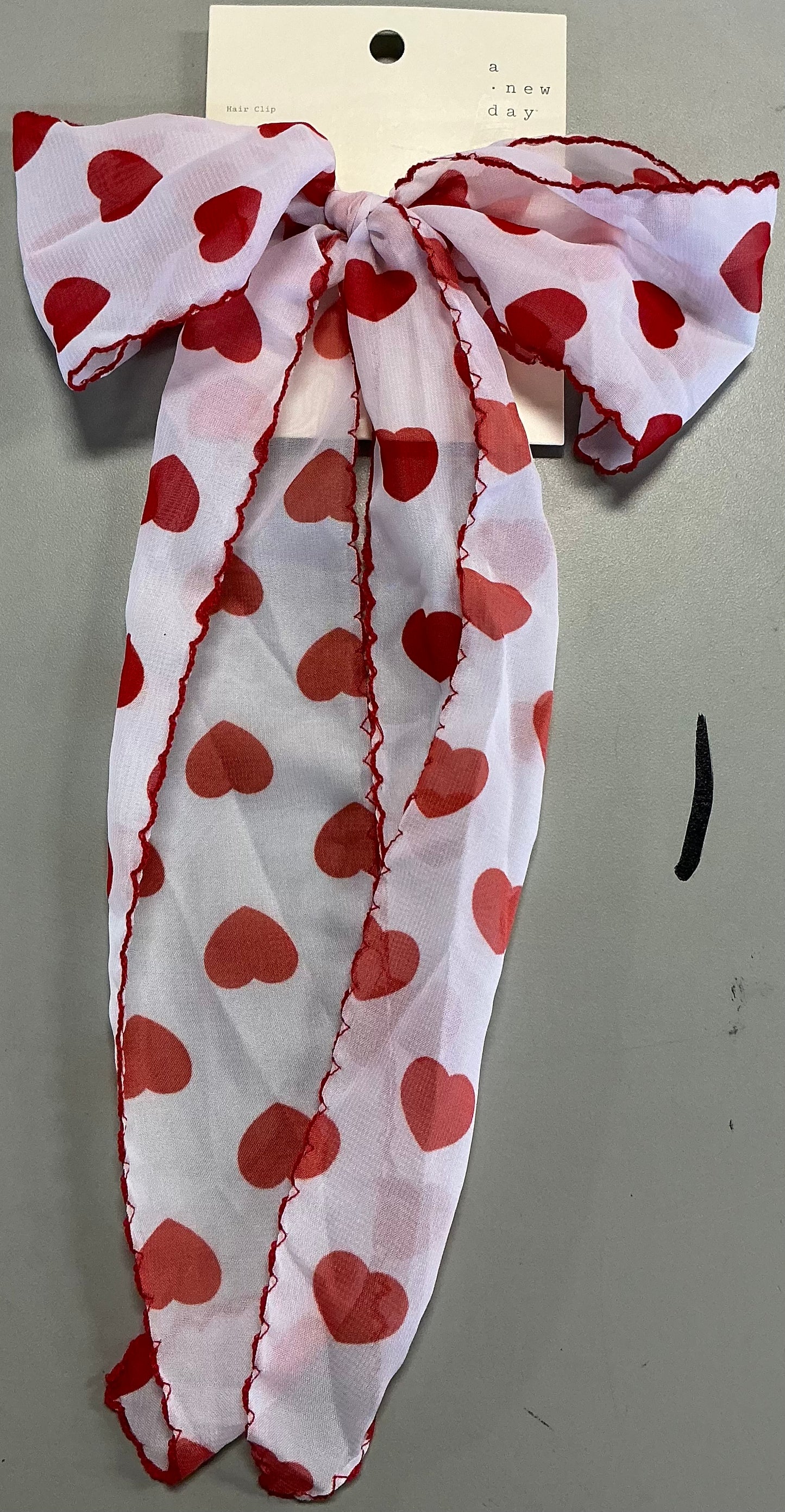 Hair bow featuring a red heart print and red stitching along the edges