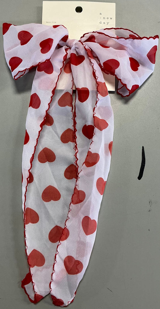 Hair bow featuring a red heart print and red stitching along the edges