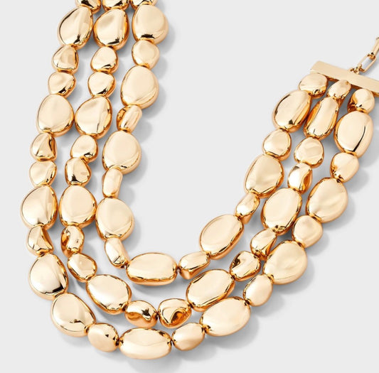 Gold-toned beaded drop necklace featuring three cascading strands of irregular pebble-like beads
